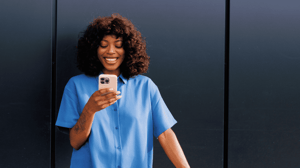 Lady standing outside, smiling at her phone