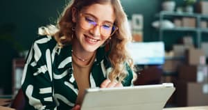 Une femme souriante qui tient un iPad dans ses mains.