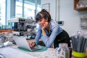 Coffee shop owner reviews fraud risks on a computer.