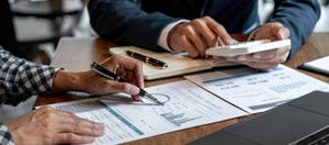 Two businessmen reviewing and calculating monthly budgets