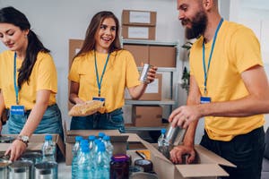 Group of volunteers in yellow shirts working in community charity donation center