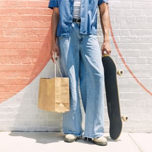 Person holding a shopping bag and skateboard