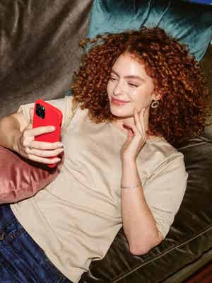 Woman lying on a sofa and holding her phone.