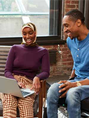Woman and man have a joyful discussion while looking at a laptop