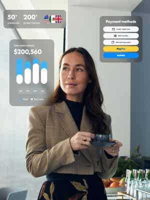 A professional woman in a sunlit office space holds a teacup and reflects on all the ways PayPal Open is helping her business.