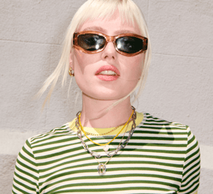 Close-up of a person wearing a striped top and sunglasses, with light reflections in the lenses