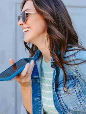 Woman standing outside in the sun holding her phone