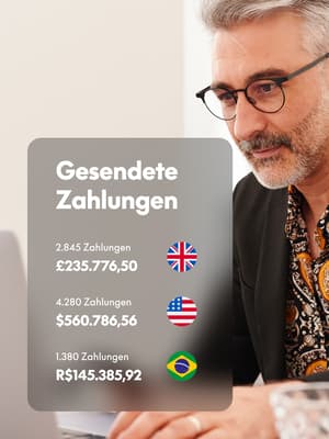 Person, die am Laptop arbeitet und ein Telefon mit einem Overlay von Geld in verschiedenen Währungen hält